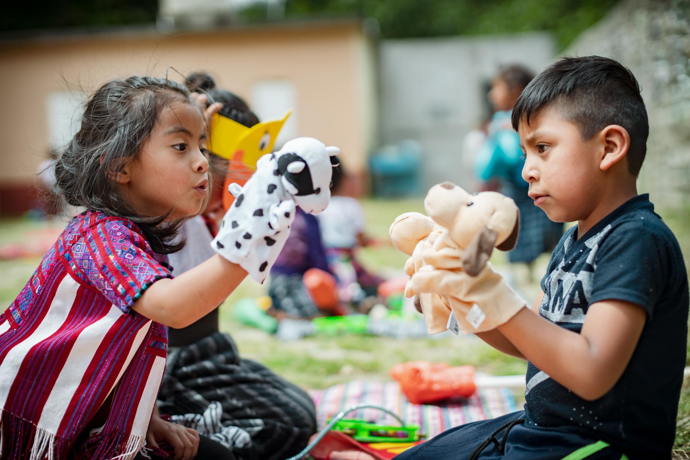 Vorschulkinder im Kindernothilfeprojekt in Guatemala sitzen sich gegenüber und spielen mit Handpuppen (Quelle: Jakob Studnar)